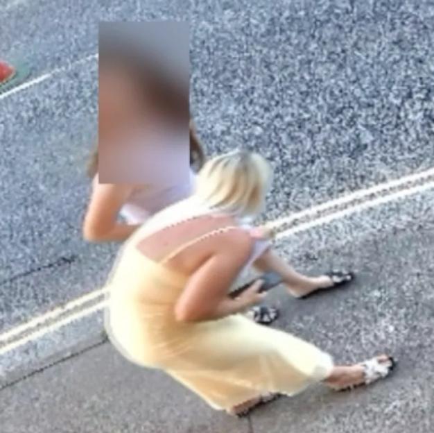 Two women sitting on the pavement.