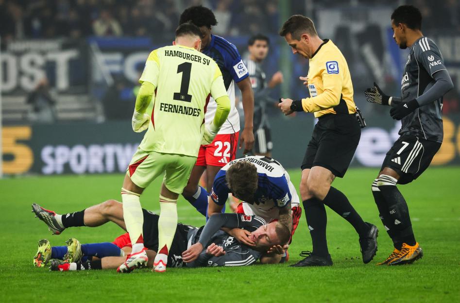 A referee watches over players on a field, some tending to an injured player.