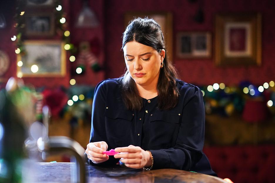 A woman looking down at a pink object in her hands.