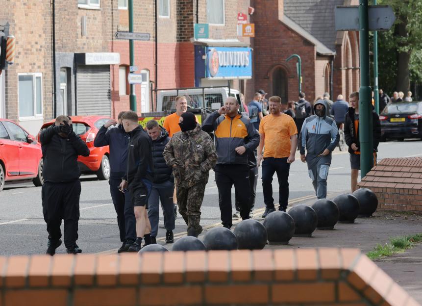 Mourners attending the funeral of Jakub Matusiak walk past buildings and cars.