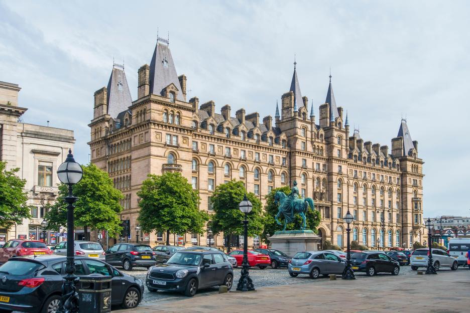 The former North Western Hotel building in Liverpool, with cars parked along the street in front of it.