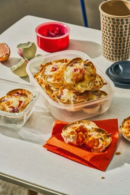 Smoked salmon and egg tortilla cups on a table with eggshells and a paper cup.