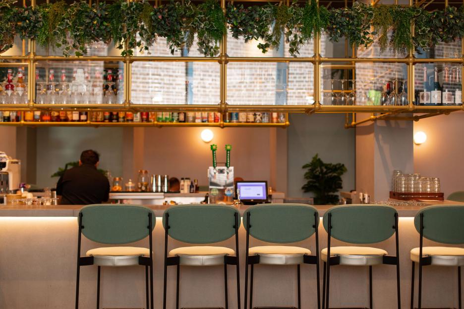 Bar with green stools and overhead shelving.