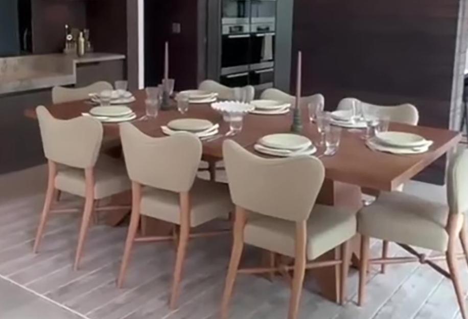 A luxury dining room with a long wooden table set for 8 people.