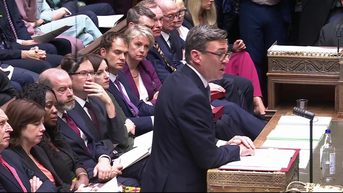 Prime Minister Andy Burnham speaking during his first Prime Minister's Questions, with cabinet members listening.
