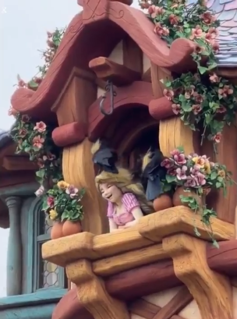 Rapunzel figure in a tower window with birds and flowers.