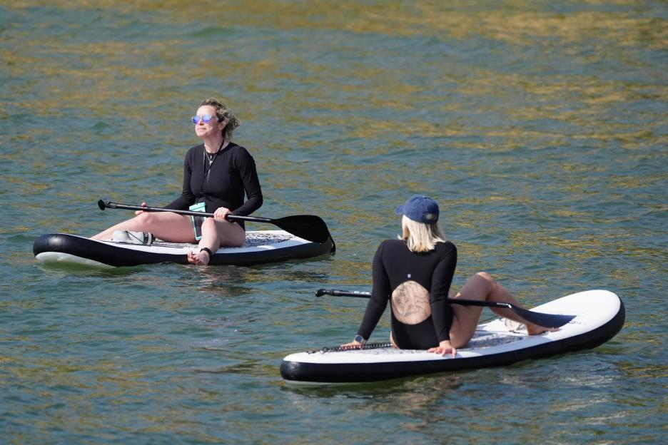 Two women paddleboarding in Cullercoats Bay, North Tyneside, UK.