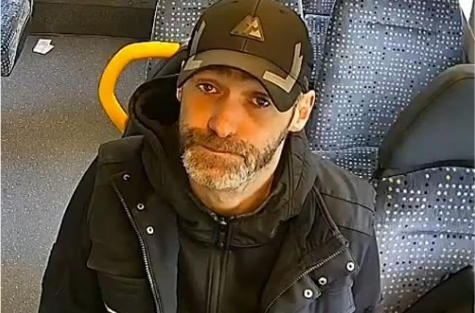 A man with a beard and baseball cap looking up at the camera.