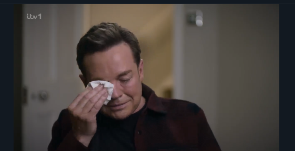 A man wiping away tears with a tissue.