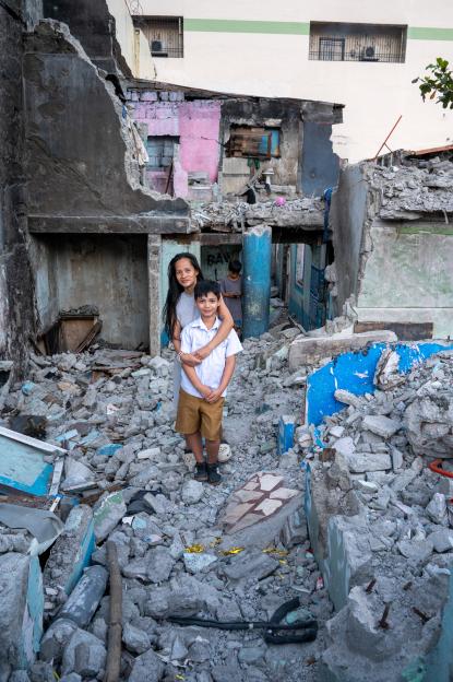 David Jurado, 8, with his mother, Abigail Ocampo Jurado, 30, outside their partly demolished home in the Philippines.