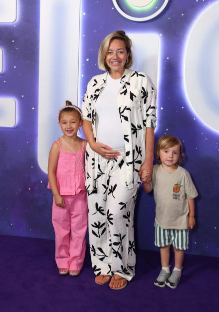 Woman smiling with her pregnant belly, standing between two young children at the "Elio" screening.