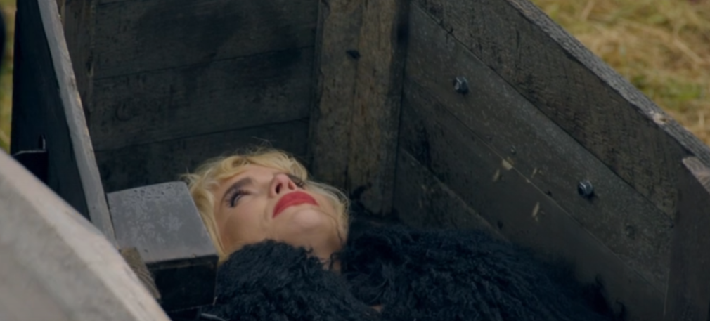 Paloma Faith lies in a wooden box, looking up.