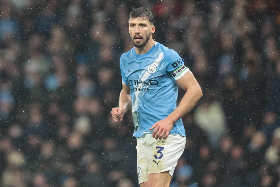 Ruben Dias of Manchester City in a light blue jersey with a captain's armband.