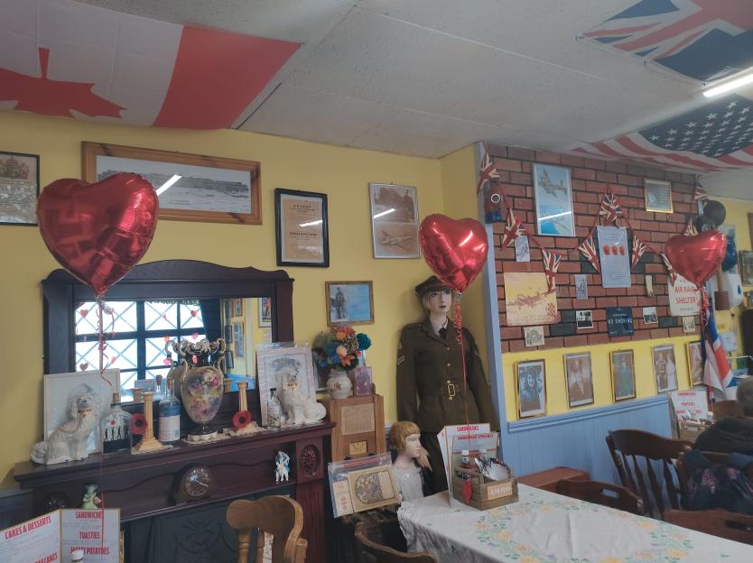 Tea room decorated with World War II memorabilia and heart-shaped balloons.