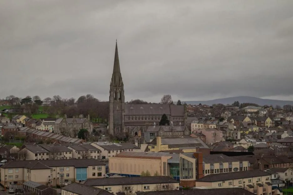 High-angle view of Derry in Northern Ireland, featuring hills in the background and a bridge on the right.