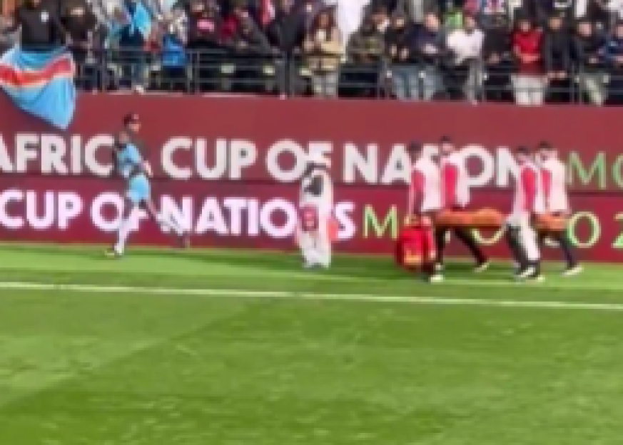 A soccer player running alongside medical staff carrying a stretcher.