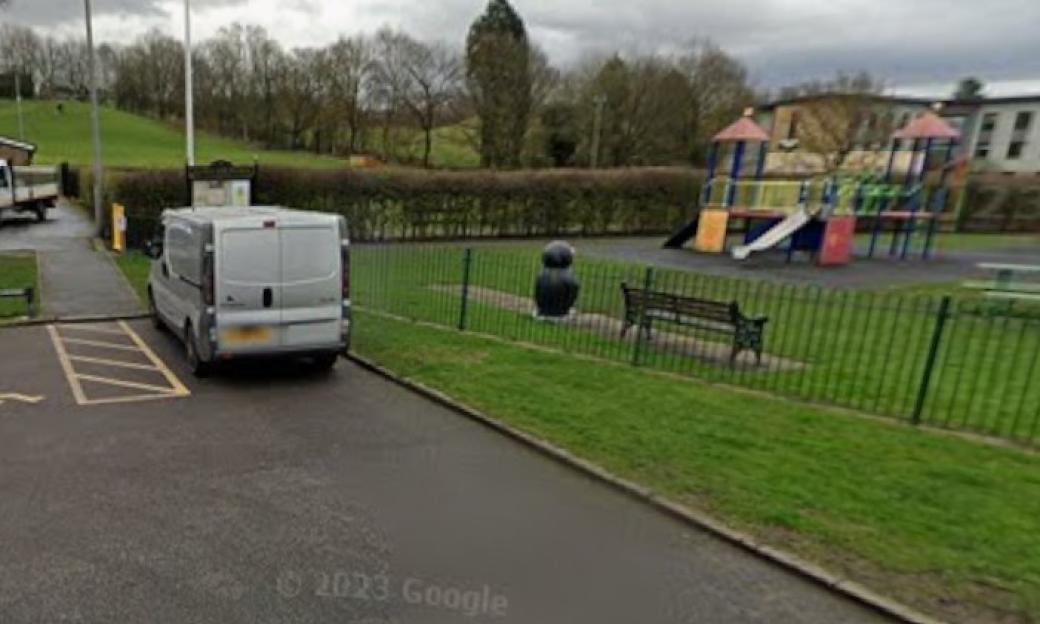 A white delivery van parked next to a children's playground.