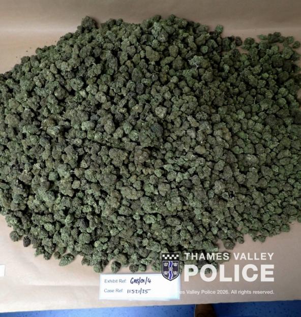 A large pile of cannabis buds on a brown surface with Thames Valley Police branding and case reference numbers.