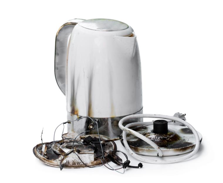 An electric kettle that caught fire and its melted and burnt base.