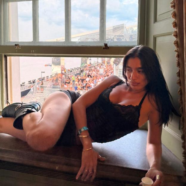 Delilah Saxena posing by a window overlooking a crowd.
