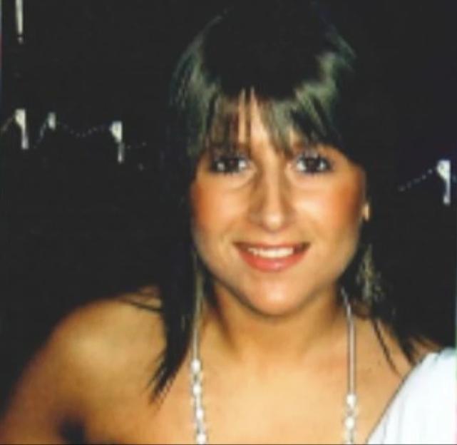 Portrait of a smiling young woman with dark hair and bangs wearing a pearl necklace.