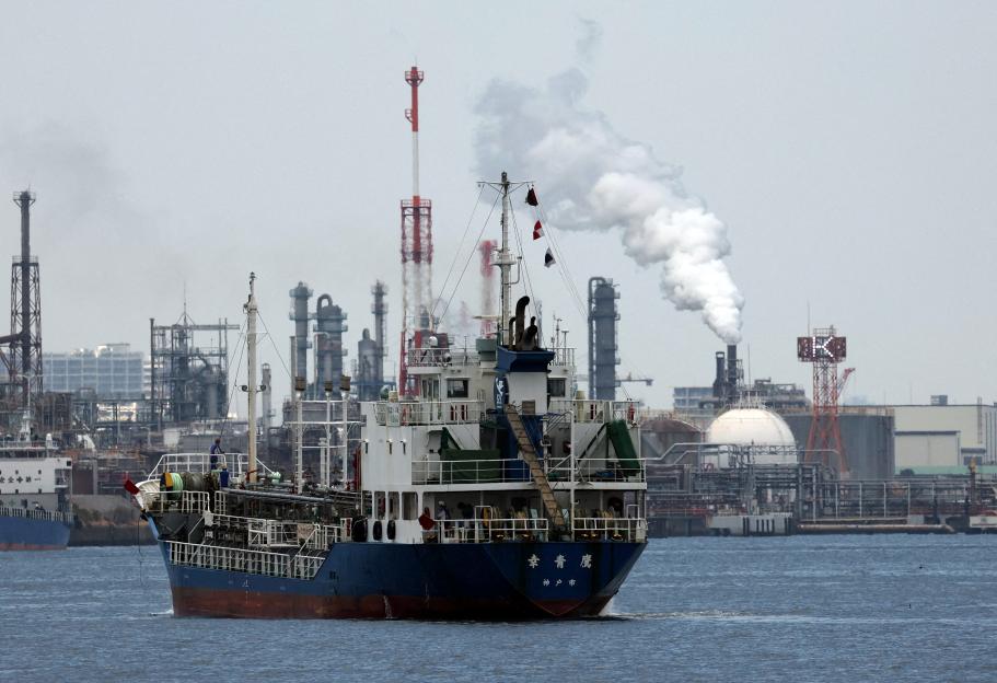 : A small tanker sails near an oil refinery in the Keihin Industrial Zone in Kawasaki, south of Tokyo, Japan
