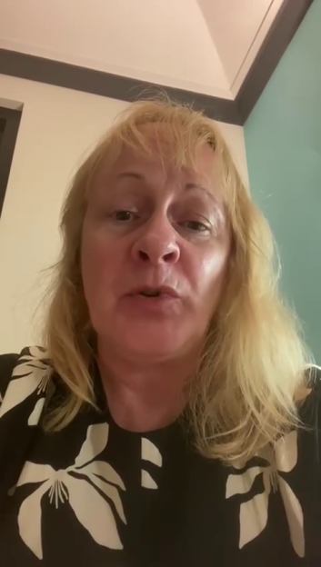 A blonde woman in a black and white floral top talks to the camera, sharing her story.