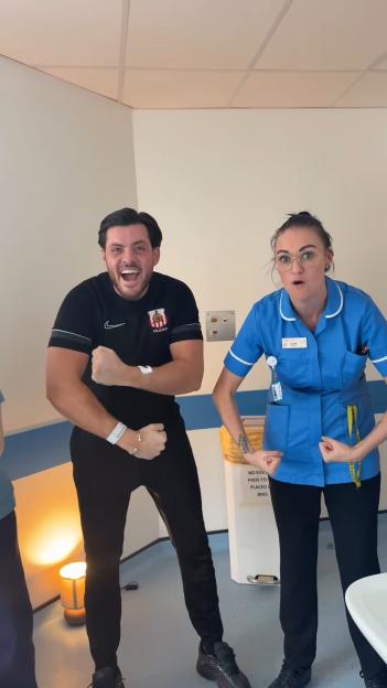 Jordan Brook and a nurse flexing their biceps in a hospital room.