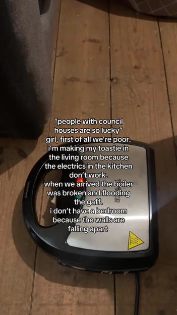 A toaster oven sits on a wooden floor next to text detailing the poor living conditions of a council house.