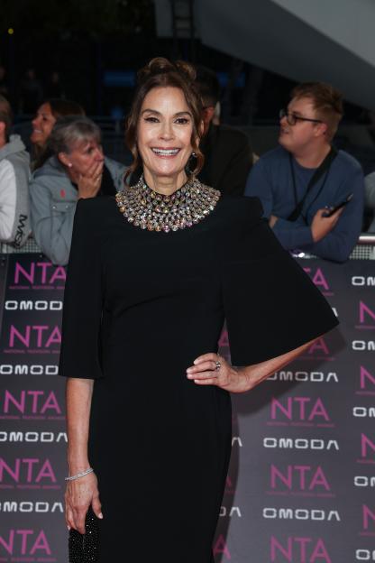 Teri Hatcher smiling in a black dress with a jeweled collar at the National Television Awards.