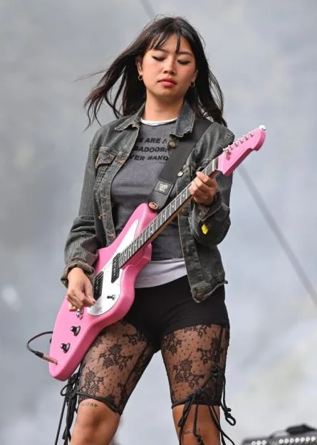 Beabadoobee performing on stage with a pink electric guitar.