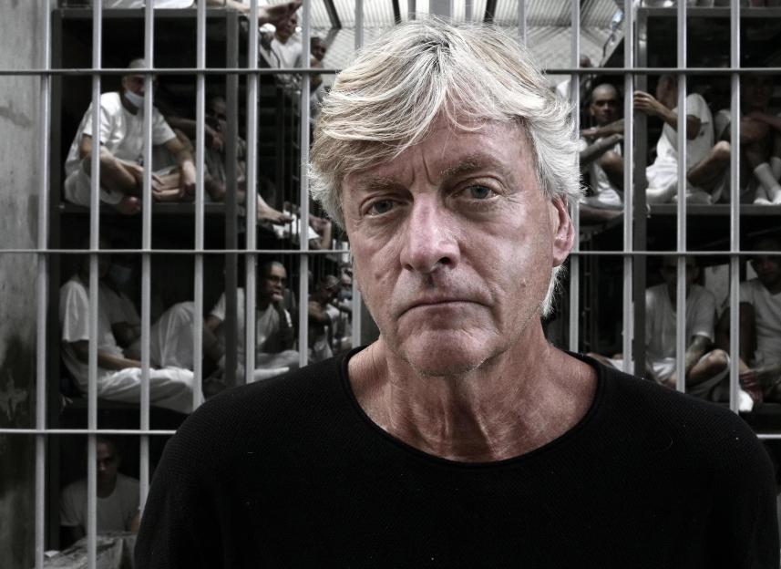 Richard Madeley in a black shirt, superimposed over a prison scene.