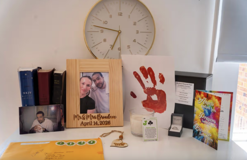 A collection of personal items, including framed photos, books, a clock, a red handprint, a candle, a ring box, and cards.