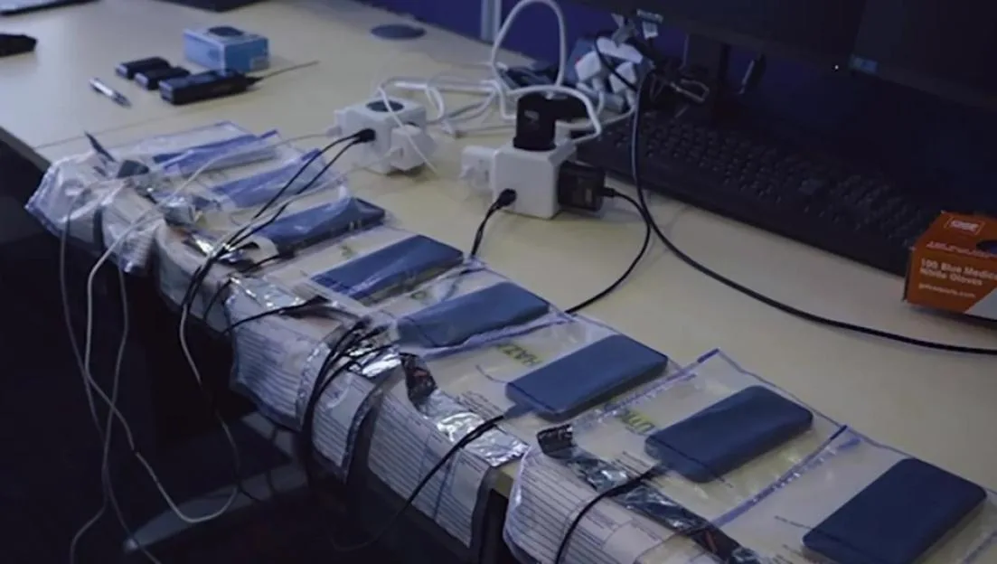 Met Police officers handling stolen phones, many of which are plugged into chargers on a table.