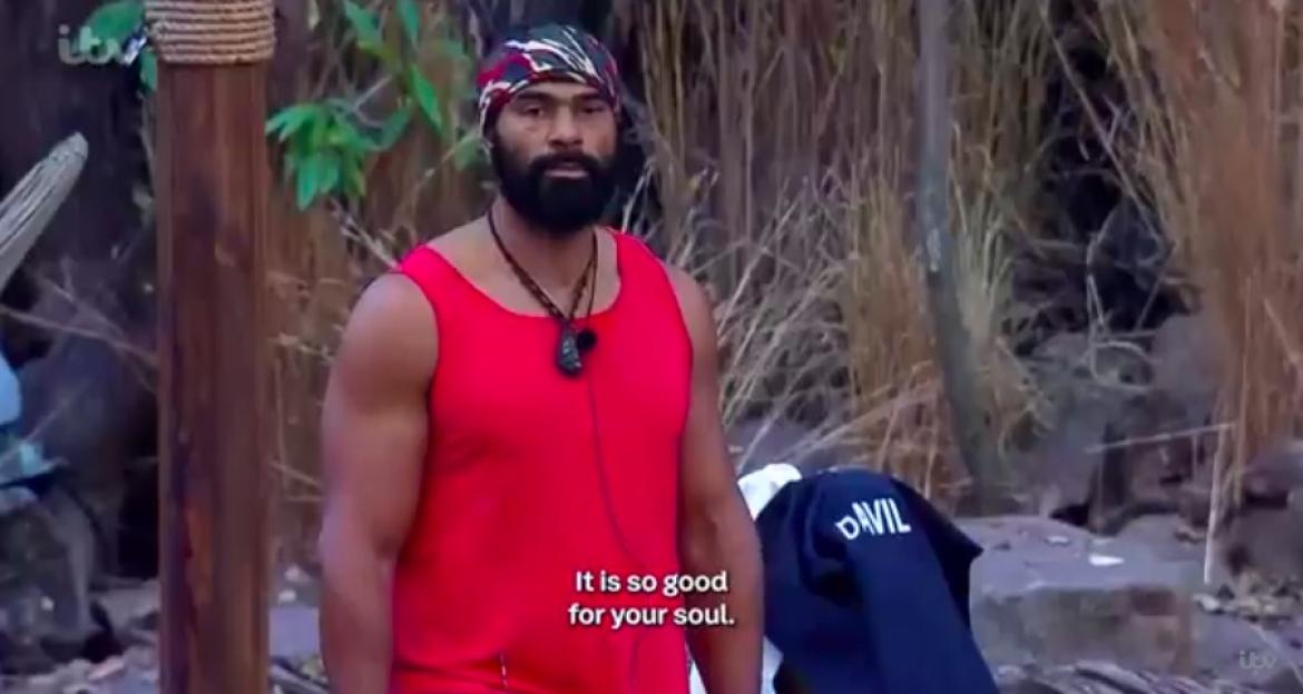 David Haye in a red tank top and patterned head wrap, looking off-camera with a stern expression.