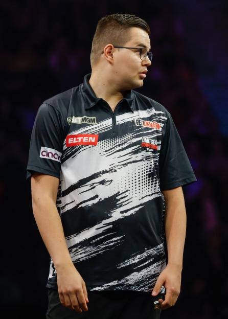 Gian van Veen looks at opponent Luke Littler and the crowd during a darts match.