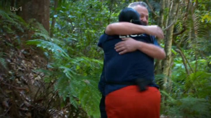 Two people hugging in a jungle.