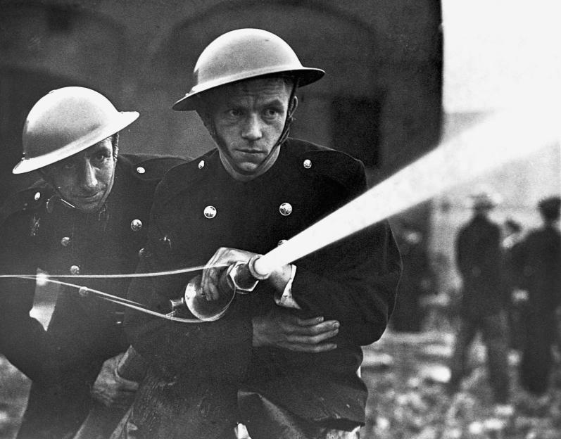 Two firefighters spraying a hose during a wartime exercise.