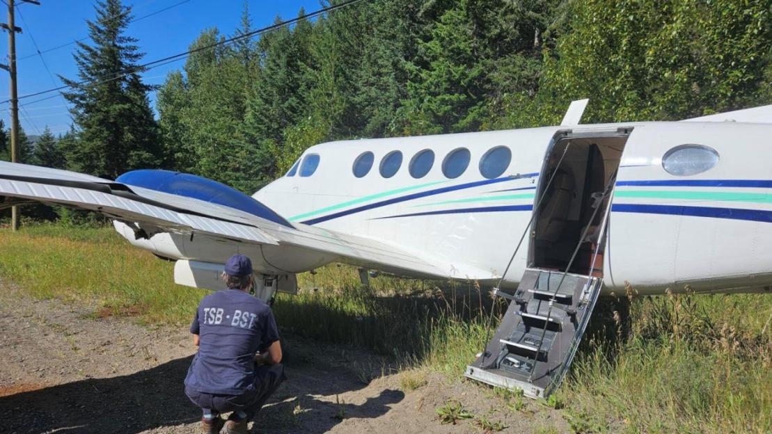 A Transportation Safety Board (TSB) investigator examining a crashed plane with a damaged wing.
