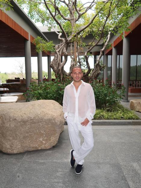 Freddie Bentley posing in a white sheer shirt and white trousers.