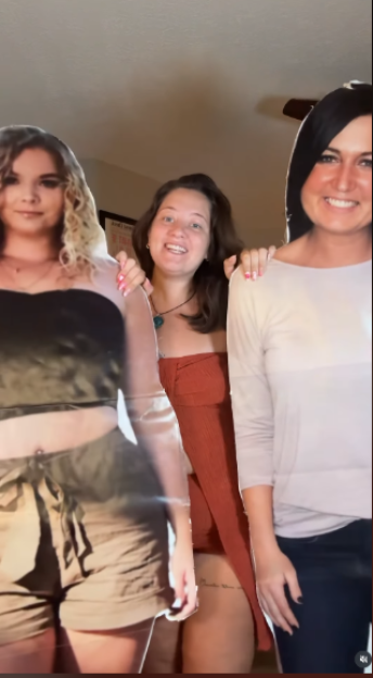 Alyssa Stout standing between cardboard cutouts of her two deceased friends.