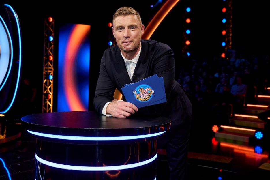 Freddie Flintoff posing in a suit on a game show set with a "Bullseye" card.