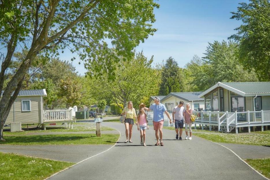 A family of five walking on a path through a holiday park with mobile homes.