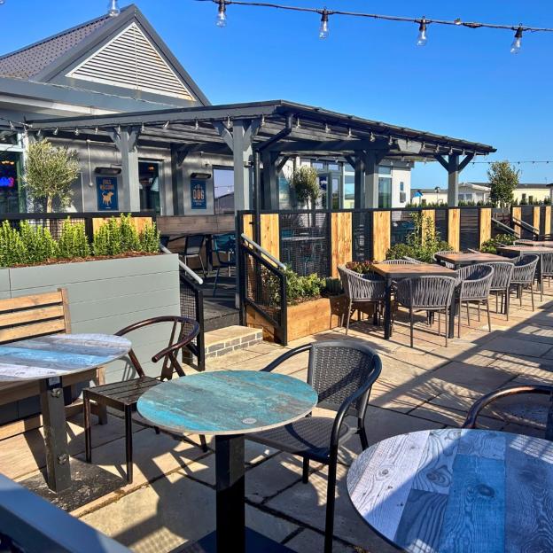 Outdoor patio seating area of a restaurant or cafe, with strings of lights overhead.