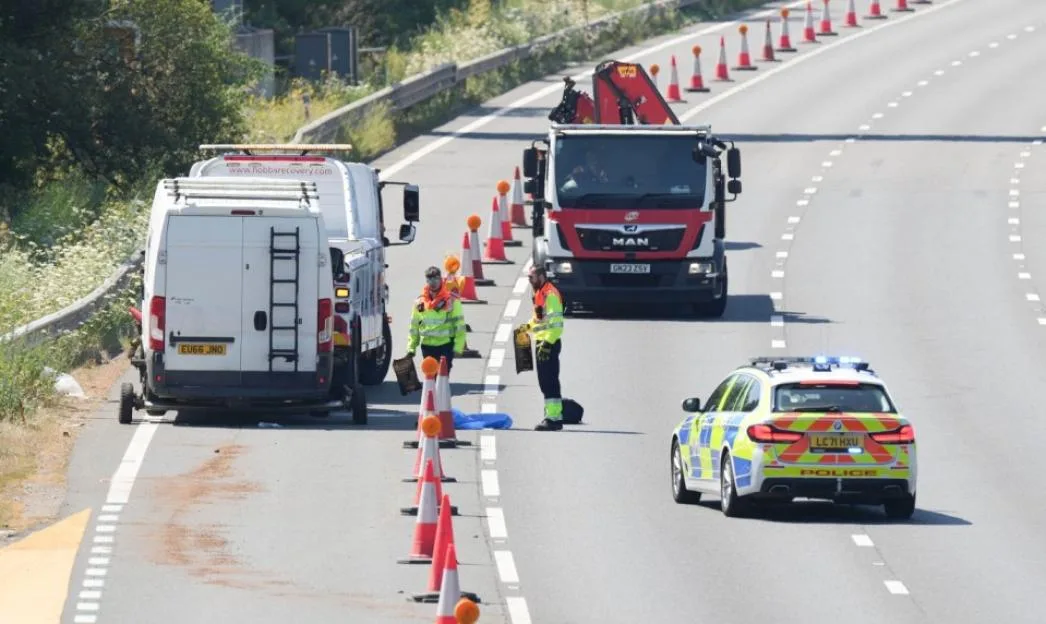 Emergency services and recovery vehicles on a highway with traffic cones.