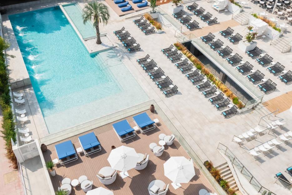 Aerial view of the L'Azure Hotel pool area, showing multiple lounge chairs, umbrellas, and beds.