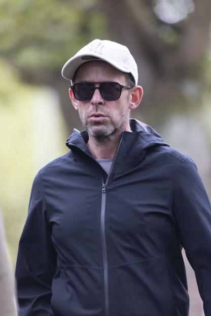 Scott Mills wearing sunglasses, a white cap, and a black jacket.