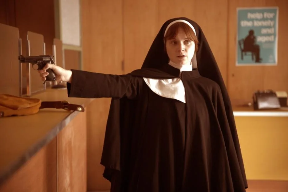 Lola Petticrew as Dolours Price in a nun's habit, holding a handgun.