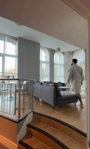 Davide walks into a bright living room with large windows.