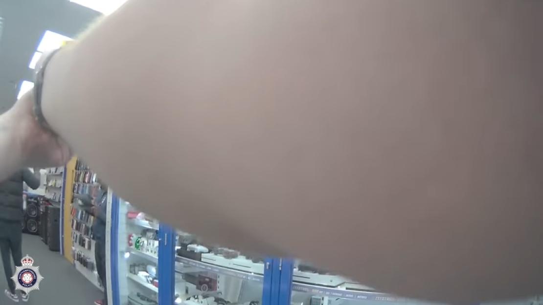 POV shot of a person's arm and a store interior with display cases.